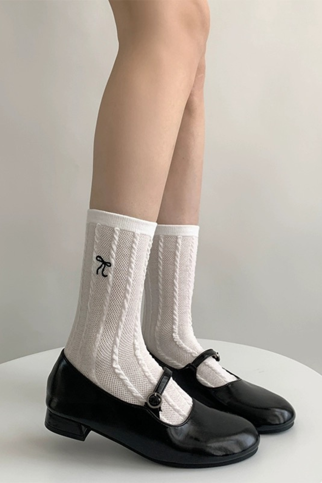 Side view of model wearing white texture bow socks with black mary jeans.