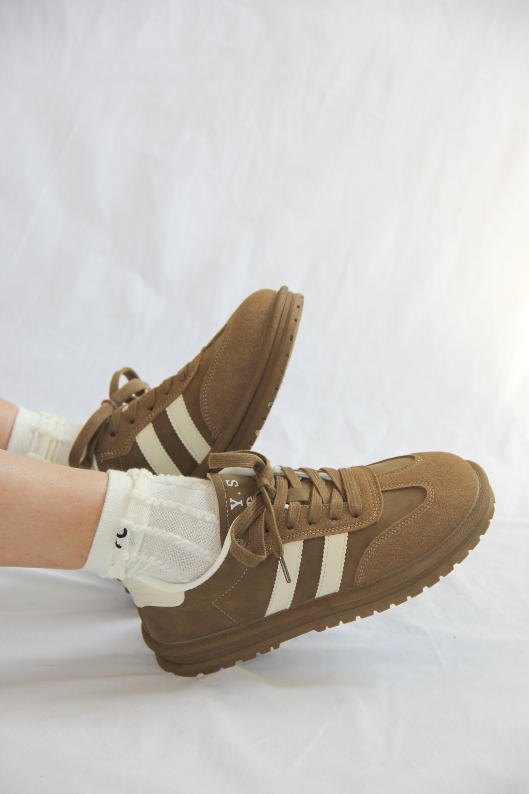 Model wearing Essen Mocha Sneakers, with a rich mocha brown suede and mesh upper, white stripes, and a comfortable platform sole.