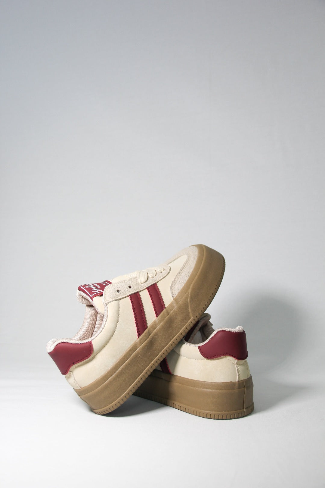 Diagonal product shot featuring Tippies beige casual sneaker with burgundy stripes