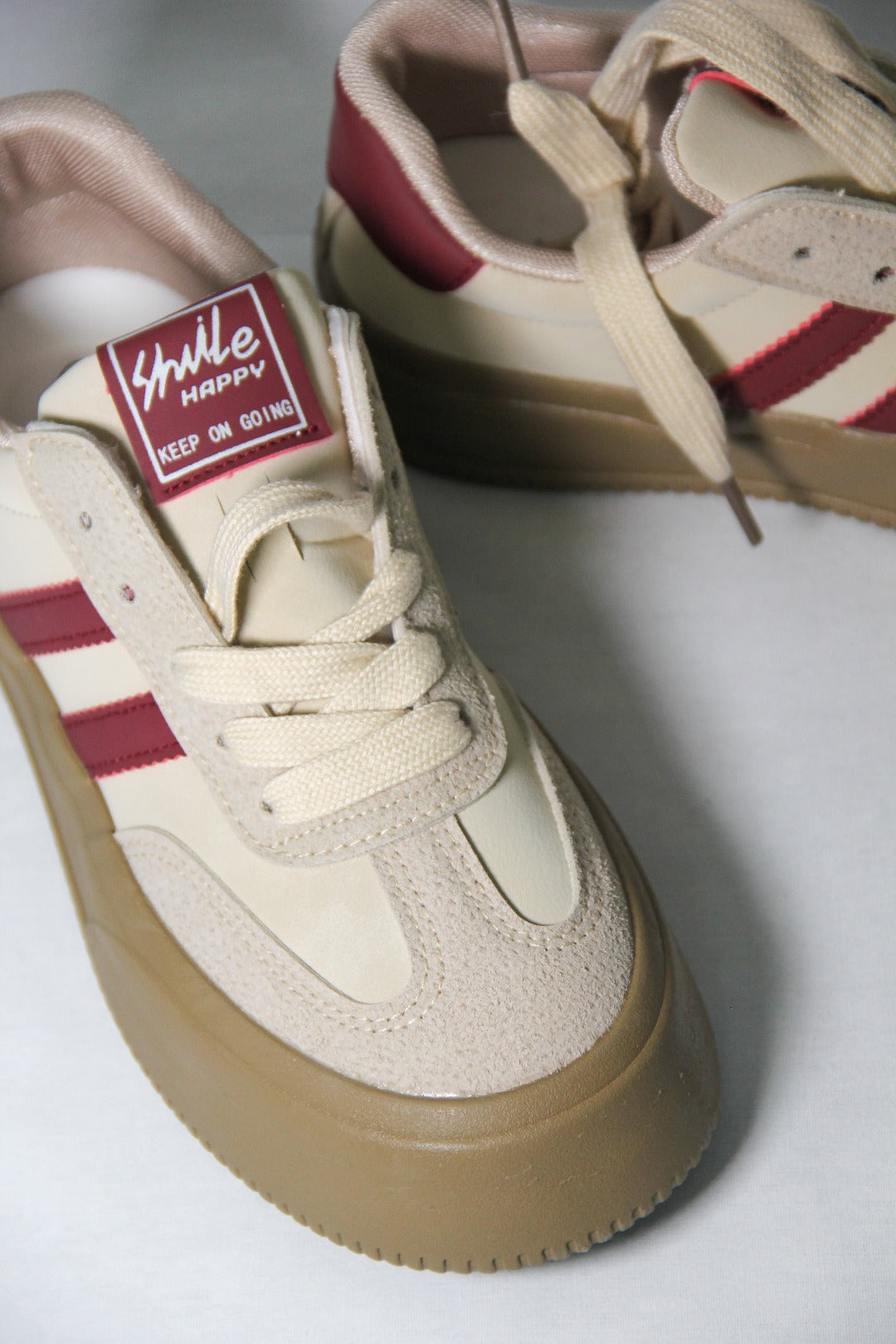 Close up view of Tippies beige casual sneaker with burgundy stripes