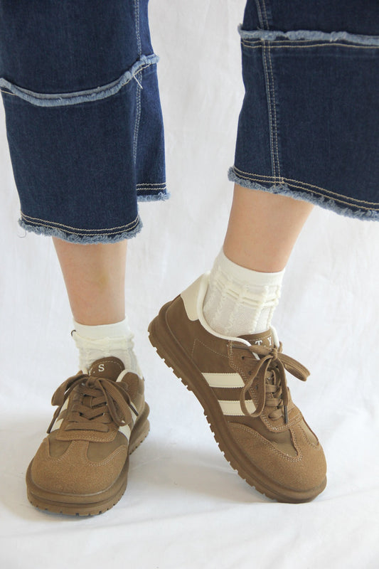 Model wearing Essen Mocha Sneakers, with a rich mocha brown suede and mesh upper, white stripes, and a comfortable platform sole.