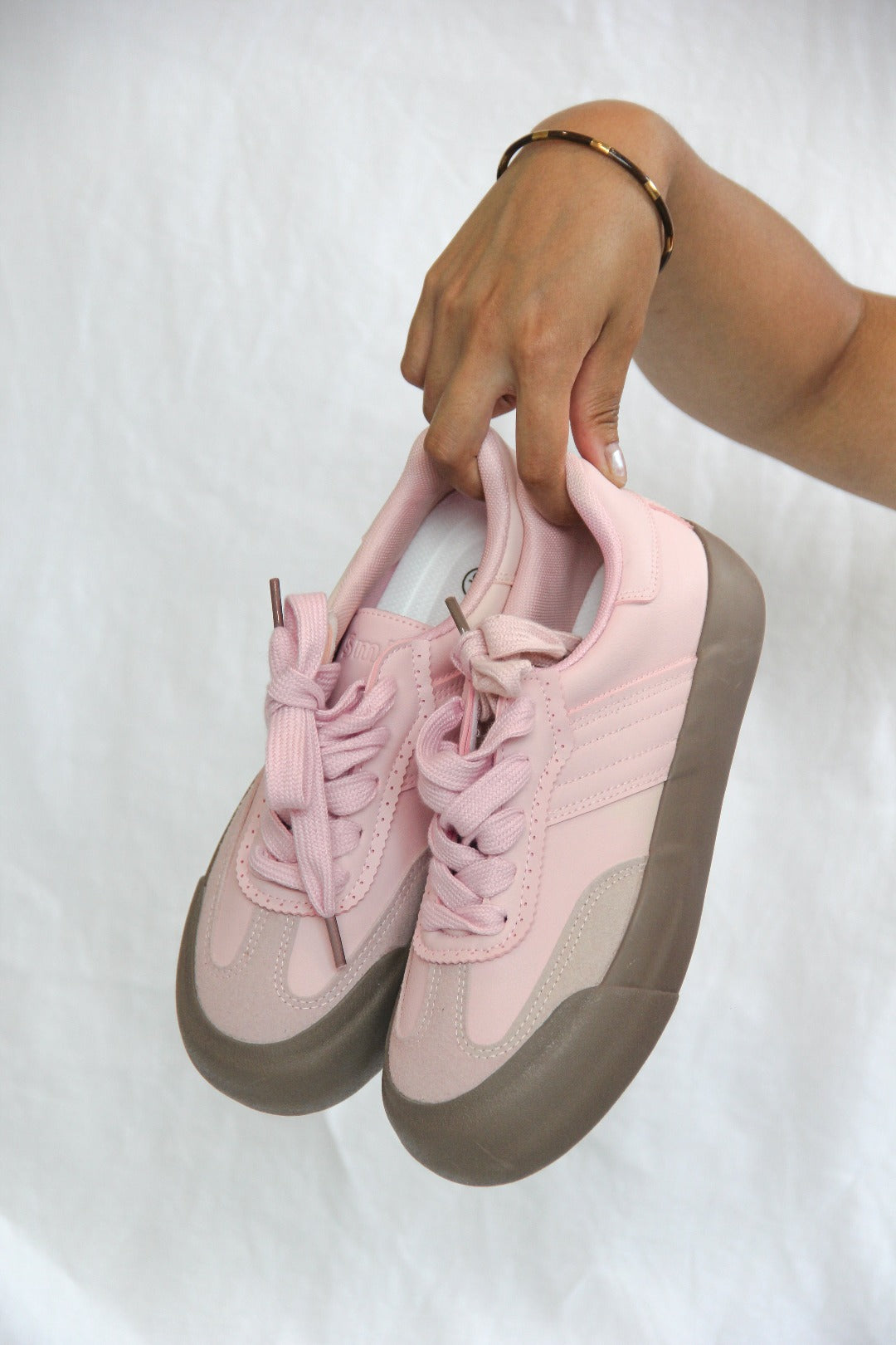 Model holding a pair of Jena Pink Sneaker